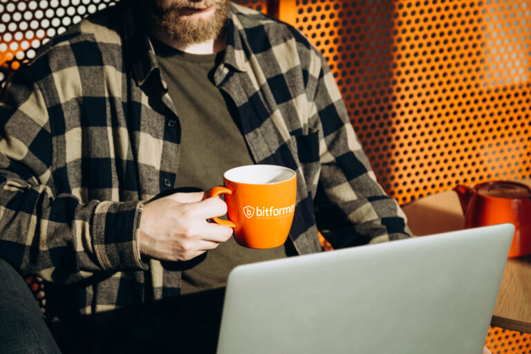 A man works with a laptop and drinks tea in a cafe interior on a