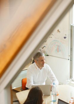 Drei Personen sitzen im Büro zusammen an einem Tisch.